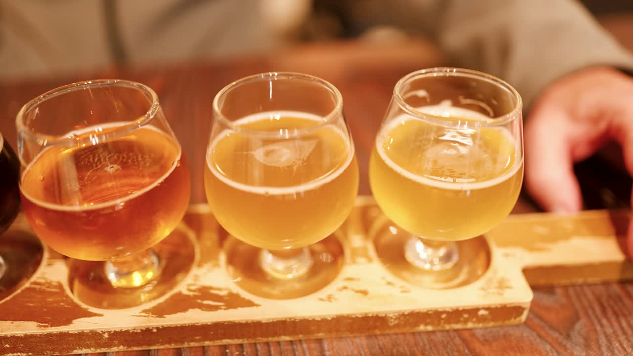 Gros plan de quatre bières artisanales différentes sur une planche de dégustation en bois dans une brasserie