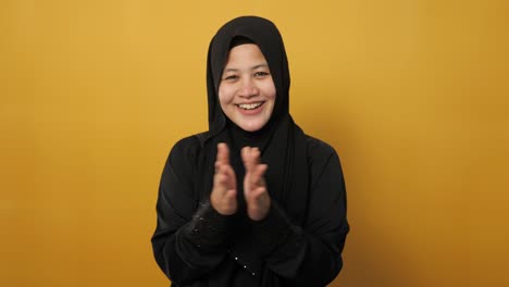 히자브를 입은 행복한 아시아 무슬림 여성, 행복하고 자랑스러운 박수를 치는 몸짓, 노란색에 반 몸 초상화