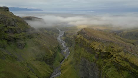 aerial panoramic view of a canyon and river as the drone flies through low lying clouds