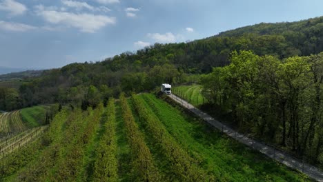 campervan driving through slovenia village road, agricultural landscape, drone shot