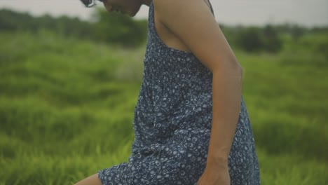 vista media de una mujer con vestido azul mirando hacia abajo en un prado césped