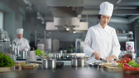 restaurante famoso en el mundo: chef asiática que cocina comida deliciosa y auténtica, corta profesionalmente verduras para una comida saludable en la cocina moderna.