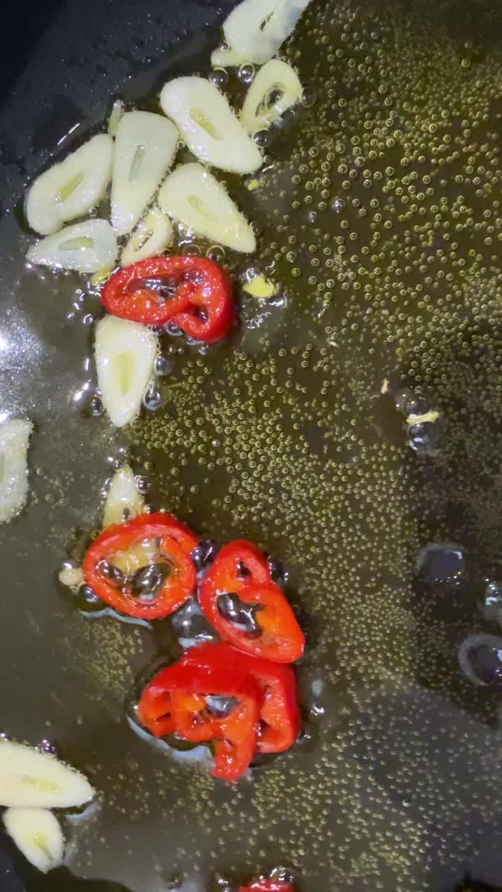 Cucinare aglio e peperoni rossi in padella.
