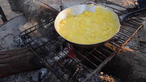 hacer huevos revueltos en una fogata en un camping en la reserva de caza del kalahari central