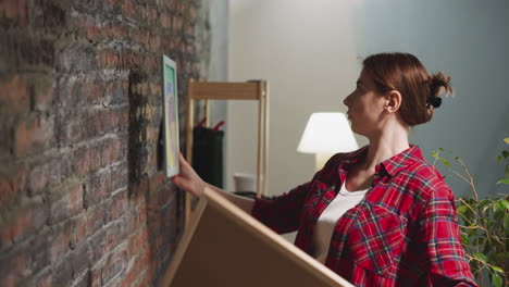 lady chooses special painting to hang on brick wall in room