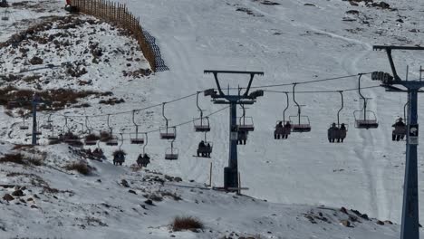 Toma-Aérea-De-Varios-Esquiadores-Y-Practicantes-De-Snowboard-Usando-El-Remonte-Para-Llegar-A-El-Colorado.