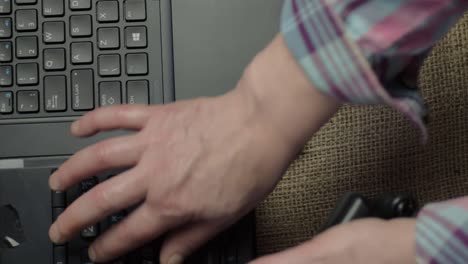 manos y dedos escribiendo en el teclado de una computadora portátil y usando un teléfono plano plano medio