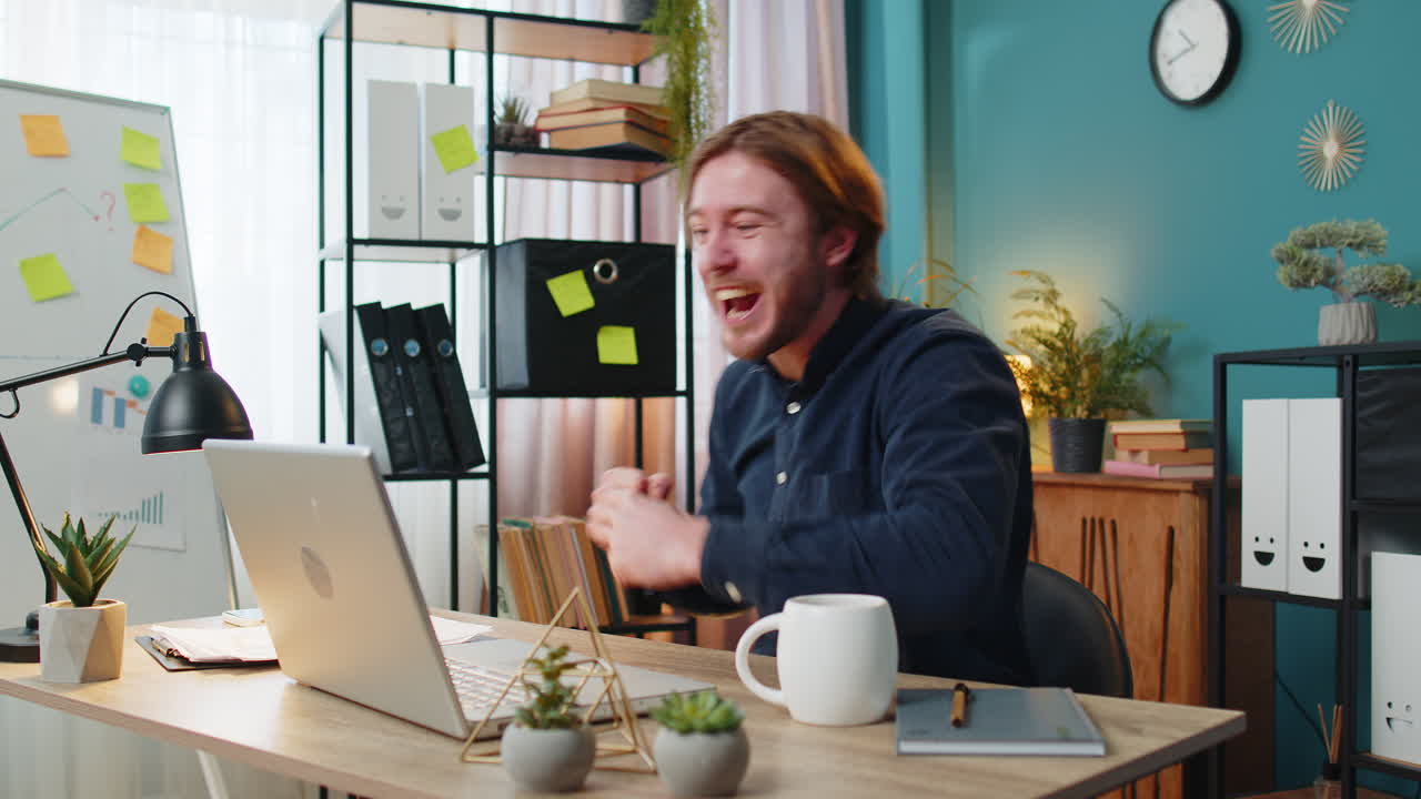 노트북에서 일하는 사업가, 갑작스러운 승리에 충격을 받았습니다.