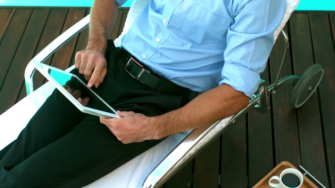 hombre de negocios usando una tableta en una silla de sol