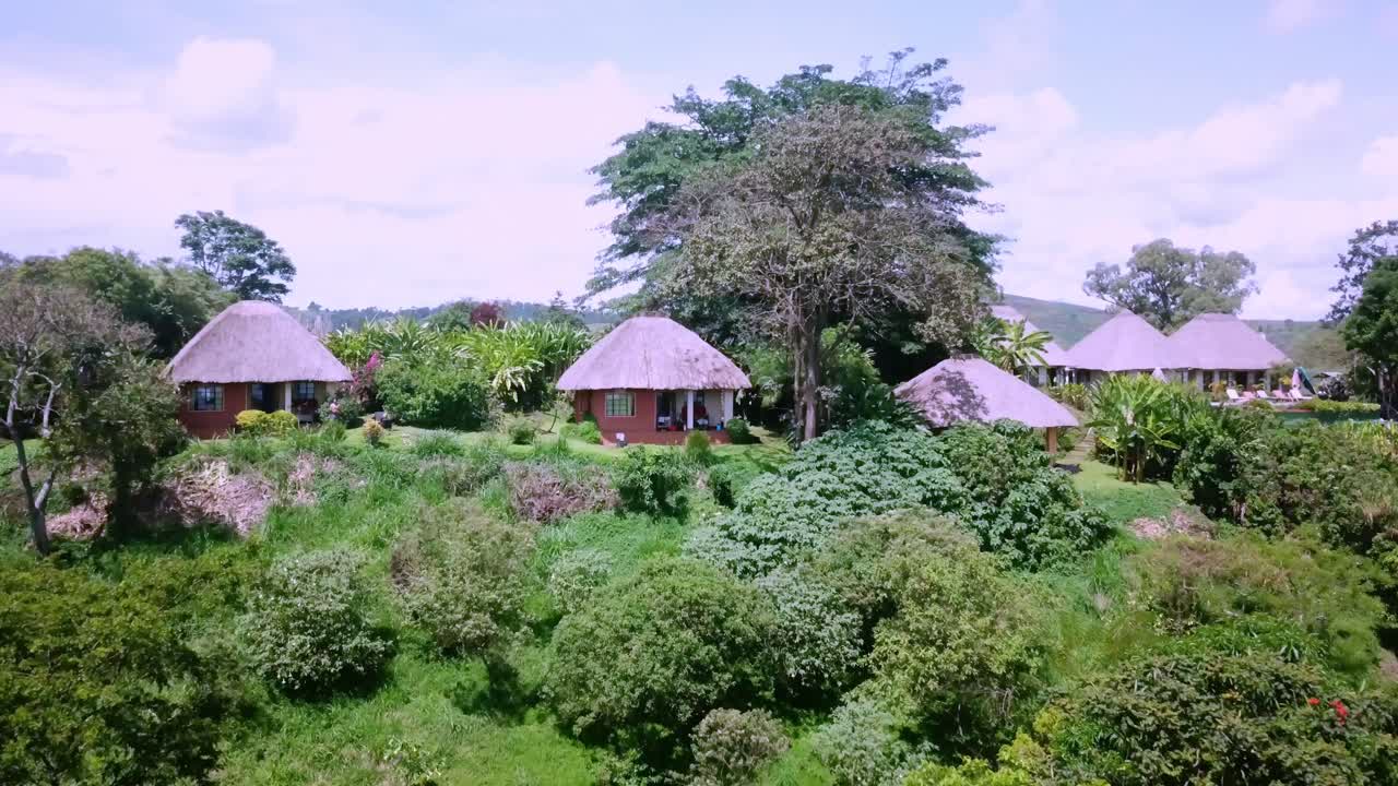 cabañas con techos de paja sobre exuberantes montañas tropicales en el oeste de uganda, áfrica