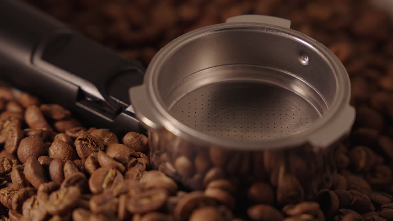 Et tomt portafilter liggende på kaffebønner.