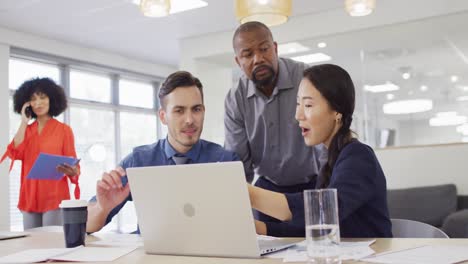 group of diverse business people using laptop and talking in office, slow motion