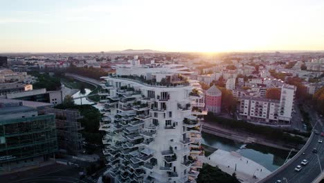 Toma-Aérea-Giratoria-Alrededor-De-Un-Edificio-De-Apartamentos-Blanco-Durante-La-Puesta-De-Sol-En-Francia