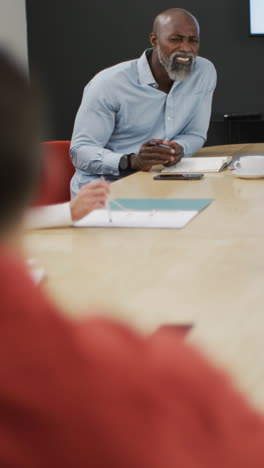 video vertical de diversas personas de negocios discutiendo el trabajo durante una reunión en la oficina