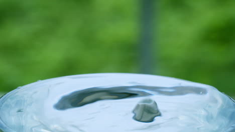 vertiendo algunas gotas de agua en un vaso de agua, creando algunas ondas y ondas en él