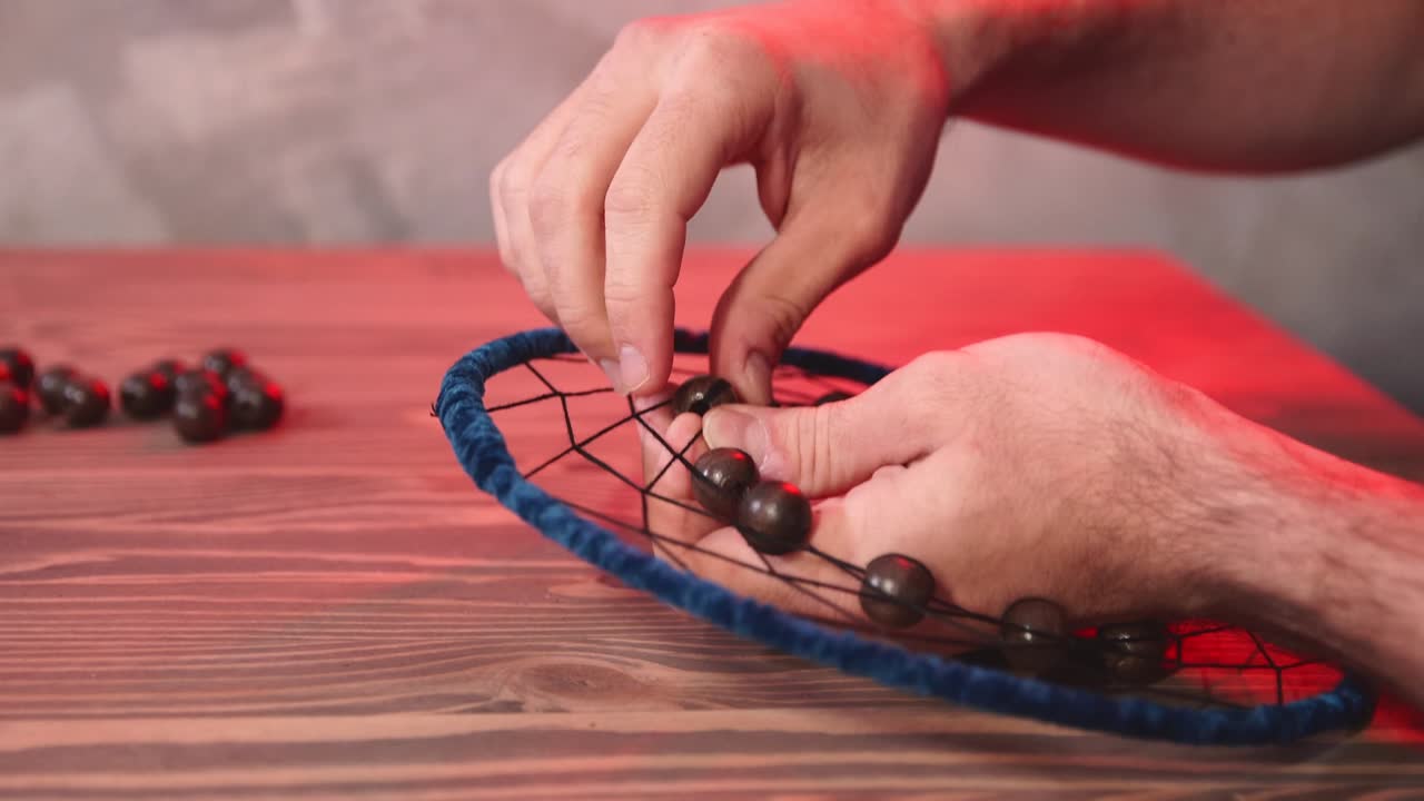 Young man creates dream catcher in workshop.