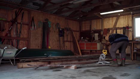scène van een persoon in de winkel met houten planken en elektrische zaagmachine
