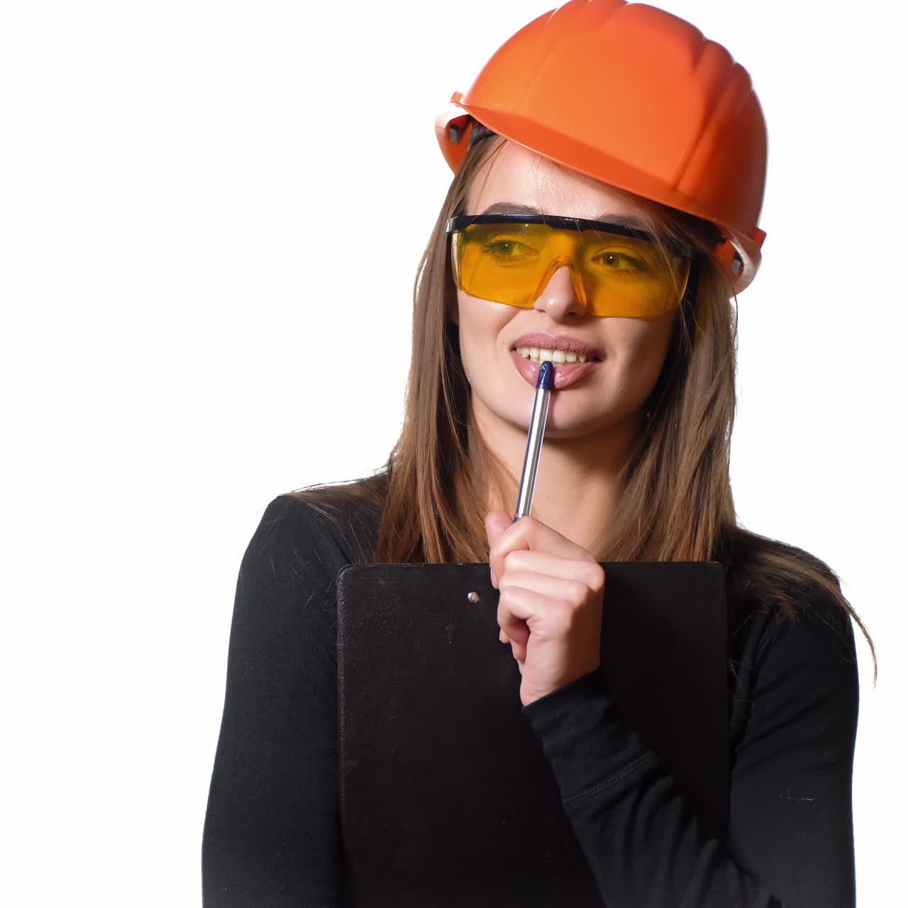 Young woman construction worker in hard hat on a white background. Attractive woman builder with notepad in hand makes the decision