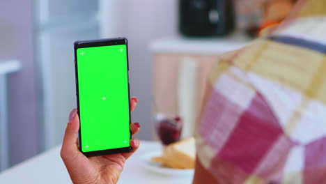 woman in kitchen holding phone