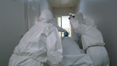 paramedics in protective suits transporting covid-19 patient