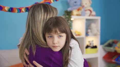 una niña infeliz y deprimida abrazando a su madre.
