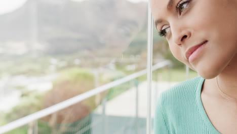 mujer biracial pensativa mirando por la ventana en casa, en cámara lenta
