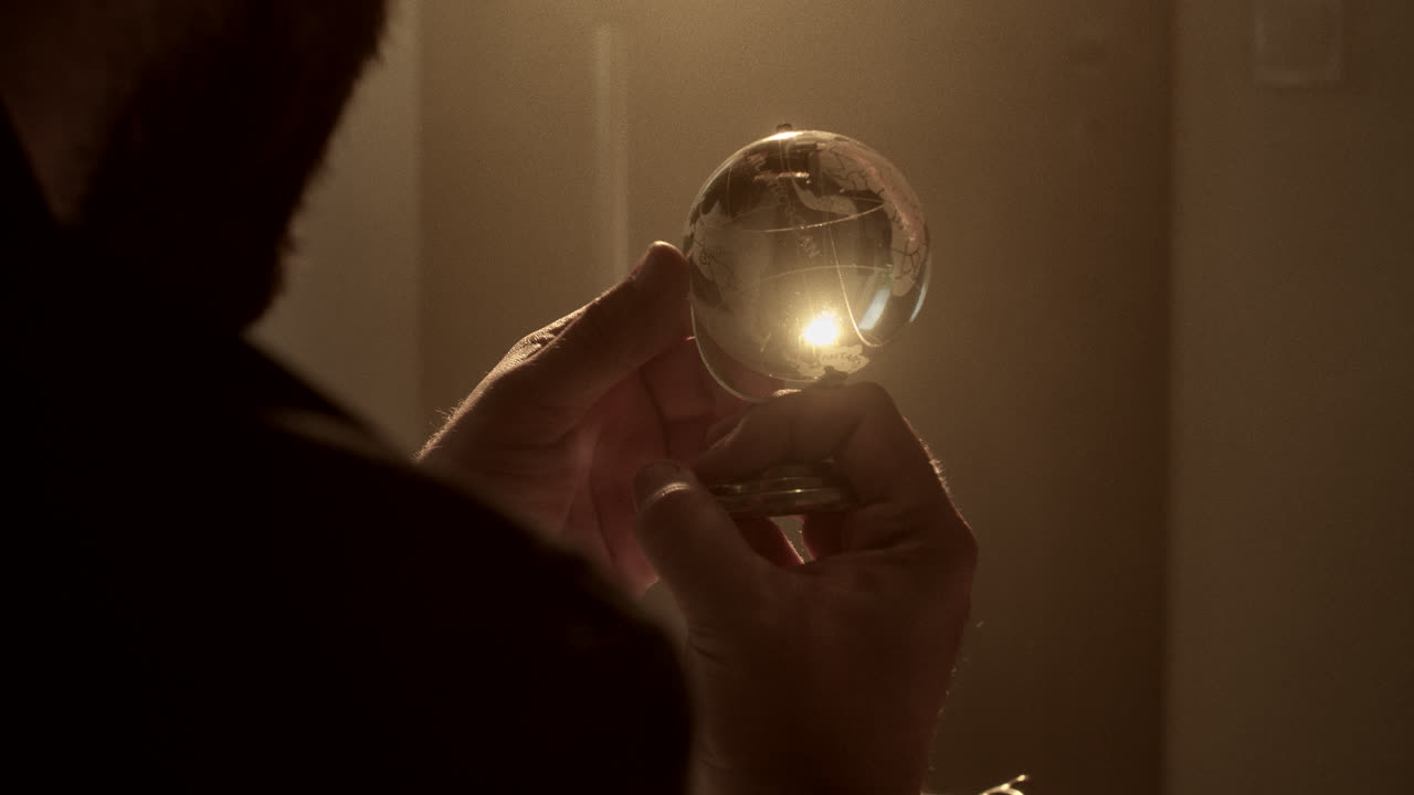 Person Examining a Small Illuminated Globe