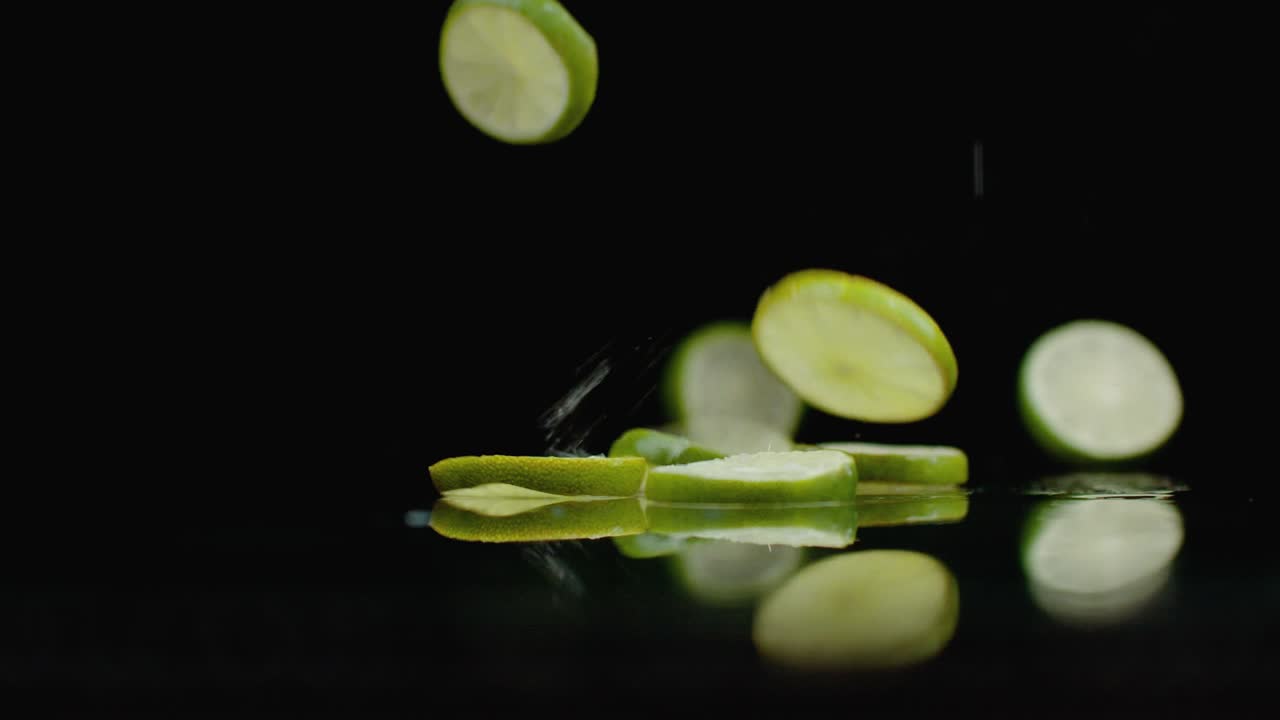 las jugosas rebanadas de fret caen sobre la mesa con reflejo y pulverización. movimiento lento anillo de lima verde