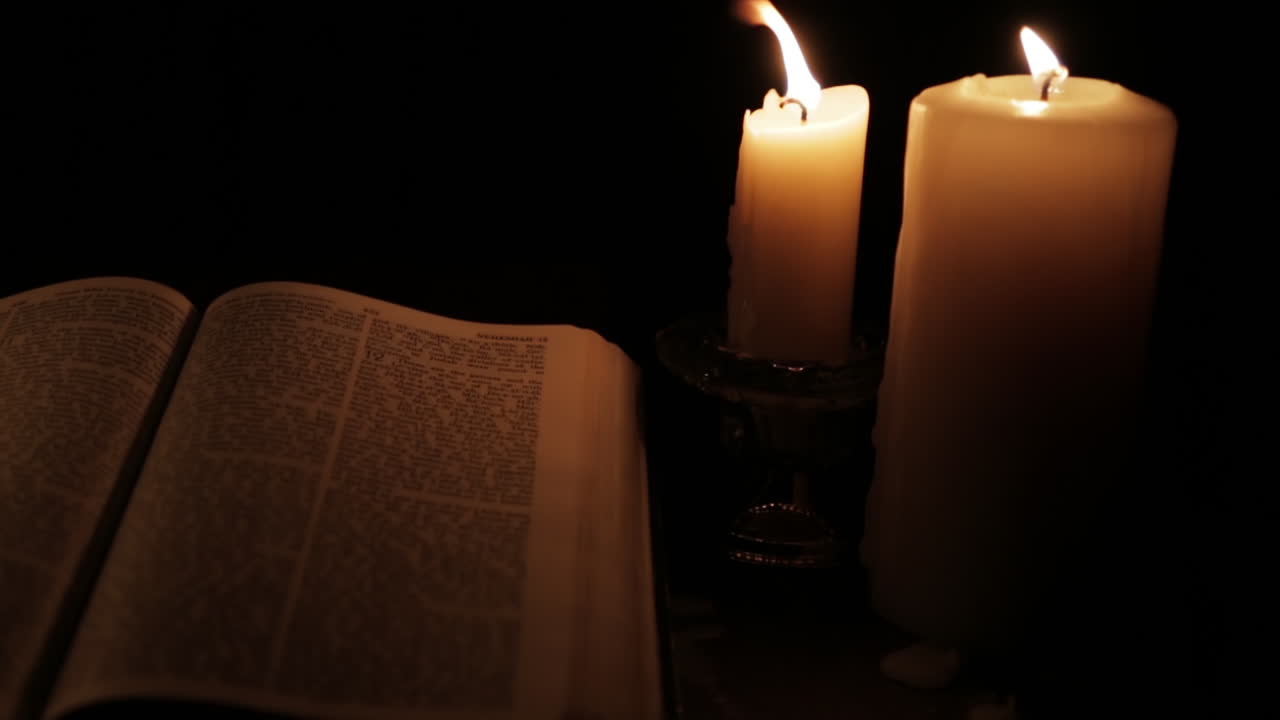 biblia santa abierta encendida por la luz de una vela en un lugar oculto y oscuro: pan izquierda lenta