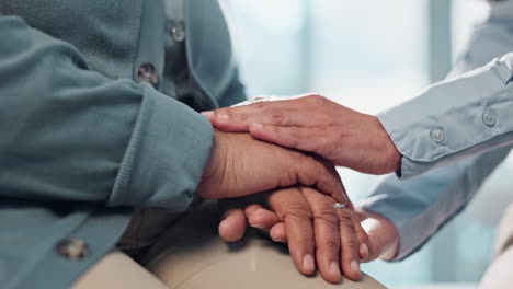 close-up of a nurse holding the hand of an elderly patient