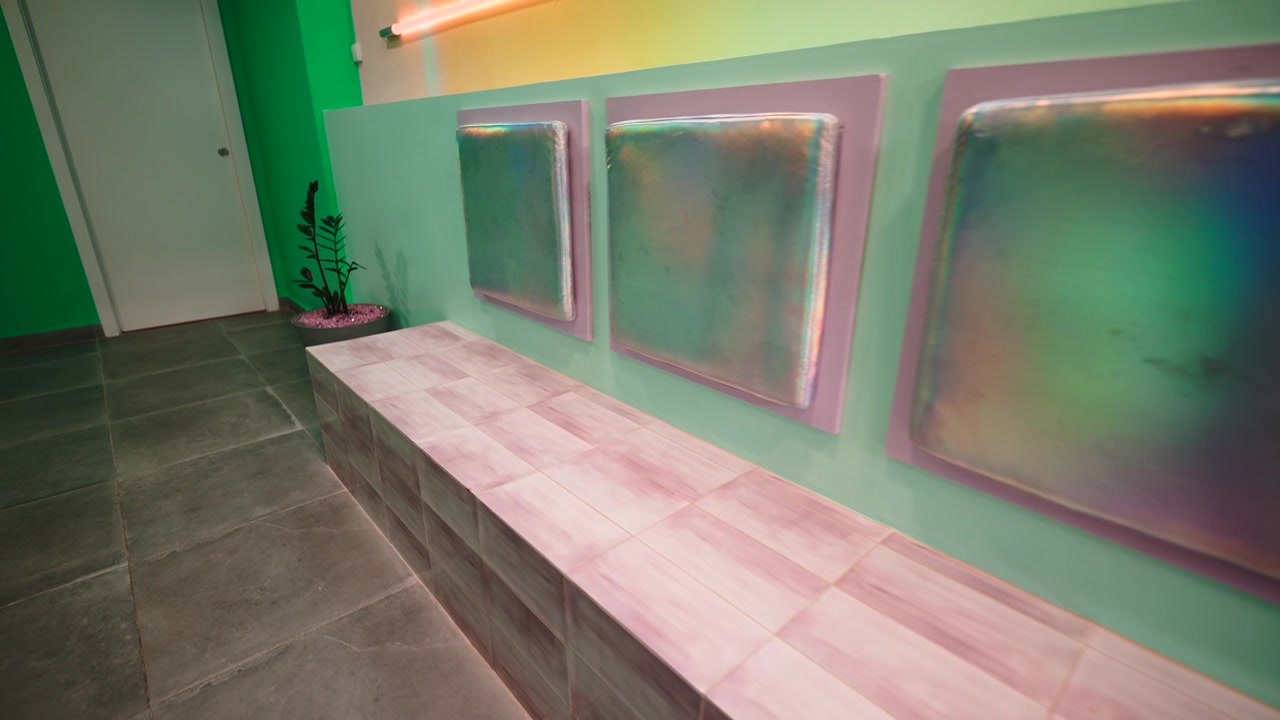 ピンクのタイル張りのベンチと玉虫色のウォールアートがあるモダンなインテリアデザイン