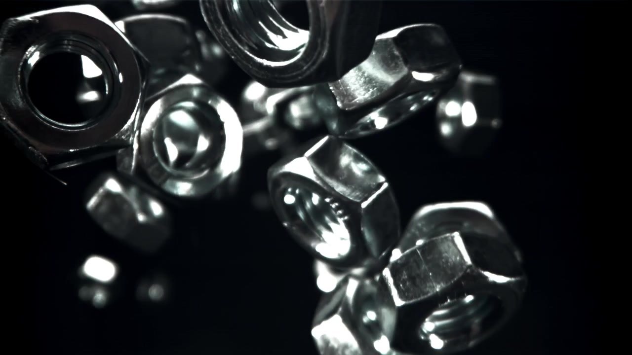Shiny Metal Nuts Falling Slowly Against a Dark Background