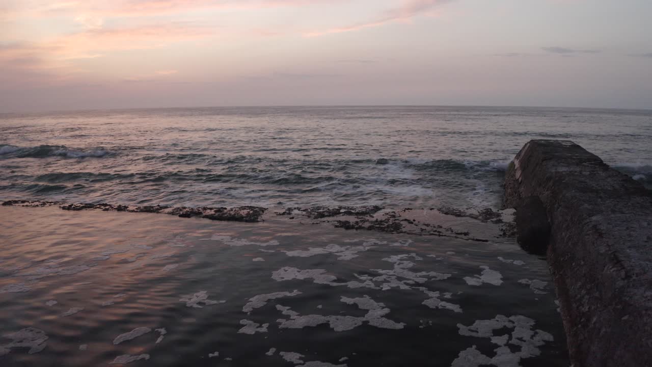 Drone flying at low altitude along pier of Hendaye, sunset, France. Aerial forward, copy space