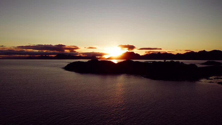 Voando diretamente em direção ao pôr do sol incrível sobre os fiordes nas Ilhas Lofoten, Noruega.