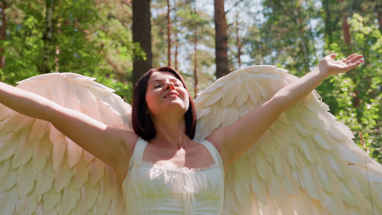 Beloved of Eros spreads radiant angel wings and embraces warmth of nature in green forest as sunlight glows softly around her, creating ethereal atmosphere of love