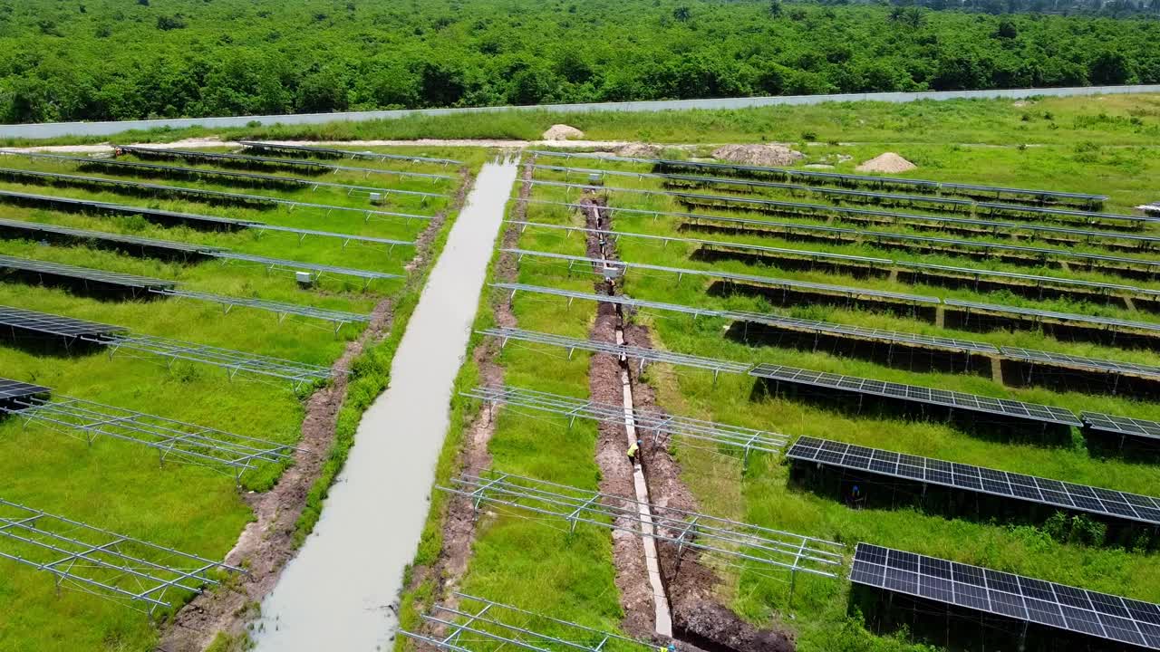 접근 도로에 정지 된 물과 함께 태양 농장에서 케이블 트렌치 파는 공중 낮은 시각