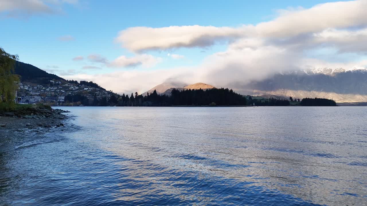Tranquil lake with mountains in the background, captured during a calm, clear day with soft lighting and gentle waves