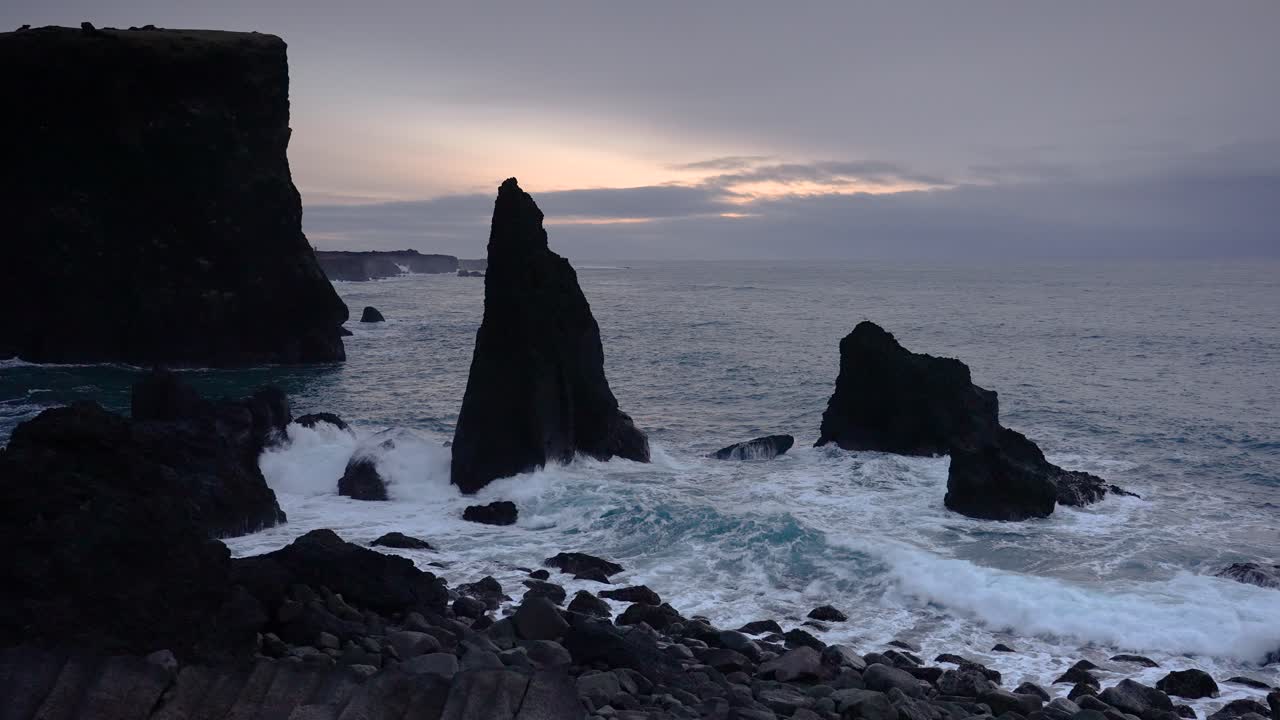 toma estática de fuertes olas rompiendo contra altas pilas de mar rocoso en la playa de reykjanes, islandia