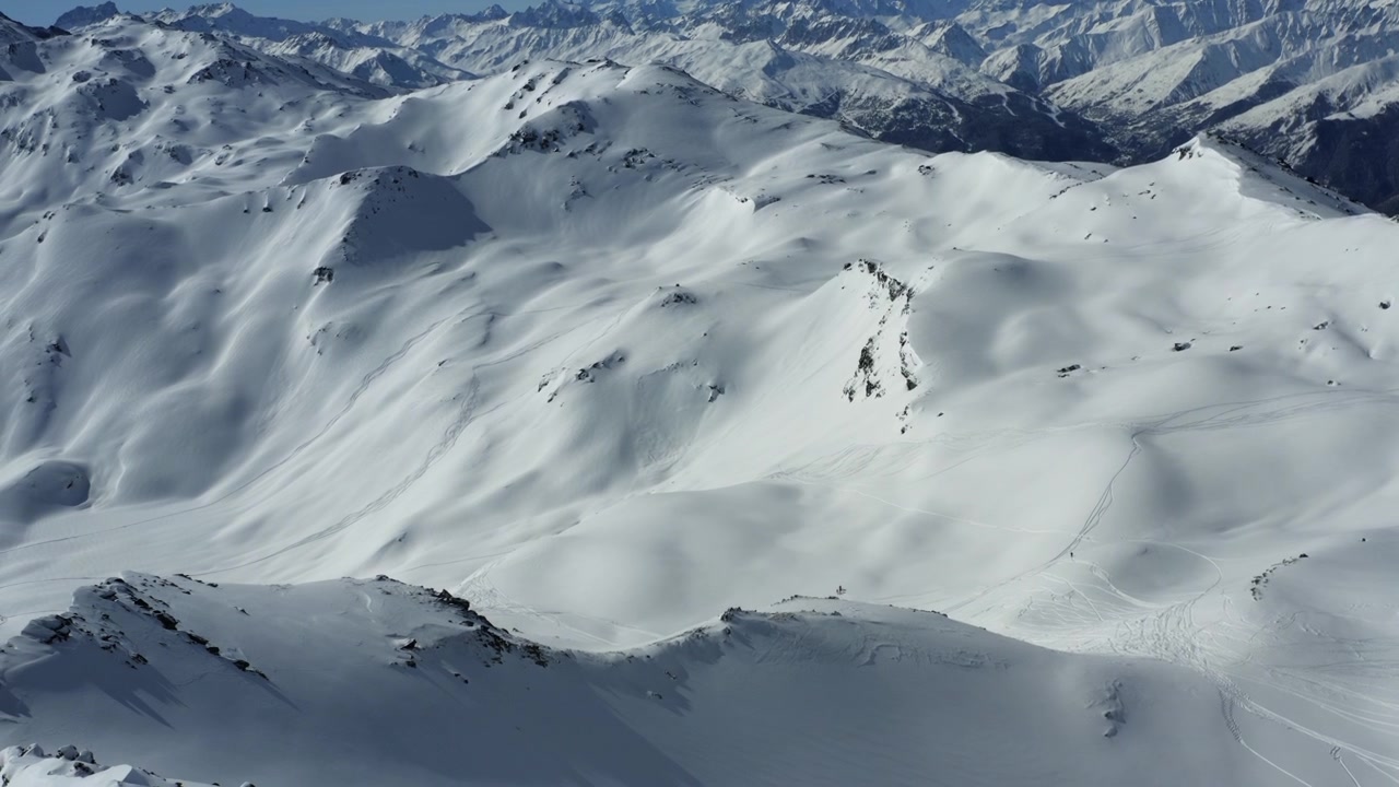 Heart of the mountain - Drone tilt down shot of breathtaking view of snow-covered mountains with peaks and ridges, smooth slopes and rugged terrain under bright daylight. Alps, France.