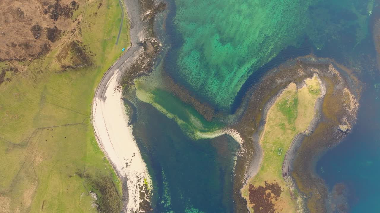 Aerial drone shot of Coral Beach on the Isle of Skye, Scotland, with turquoise waters, white sand, and surrounding green hills creating a stunning coastal landscape