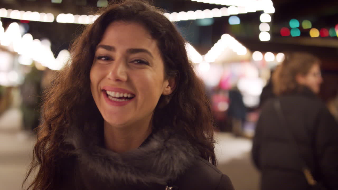 retrato de una mujer sonriente disfrutando del mercado de navidad por la noche