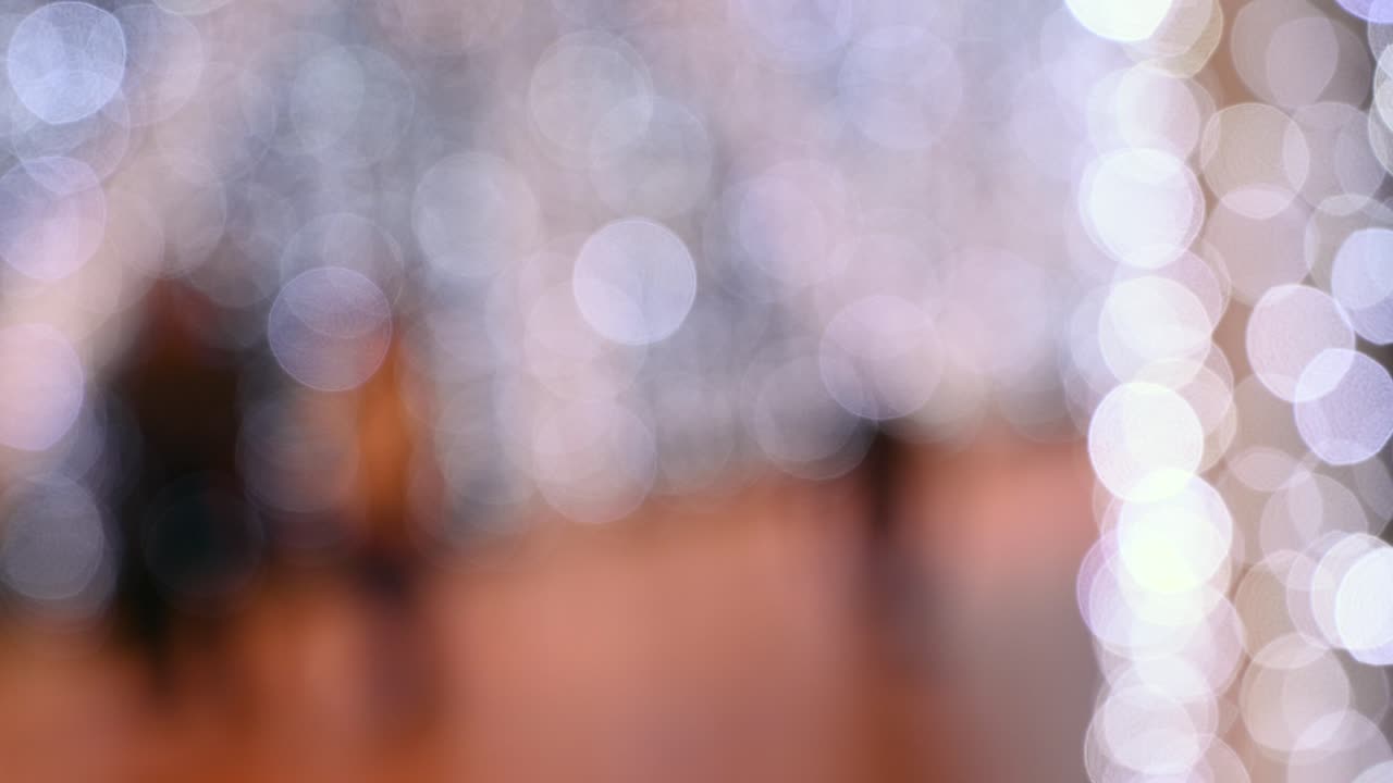 Blurred view of people walking through a shopping mall with Christmas lights on the walls
