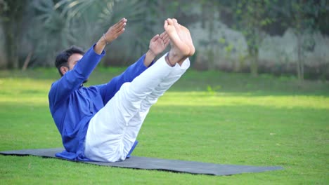 indian man doing boat yoga pose