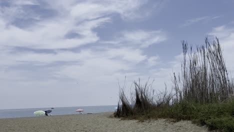 Vögel-Im-Blauen-Himmel-über-Einem-Strand-Im-Himmel-Von-Malaga-Mit-Ein-Paar-Menschen-Am-Sandstrand