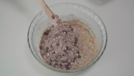 Pour-and-mix-dry-ingredients-into-batter-for-chocolate-oatmeal-raisin-cookies