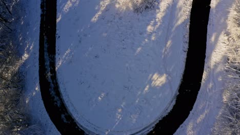 Aerial-winter-look-up-shot-from-a-tight-curved-street-up-to-a-snowy-landscape-under-a-blue-sky---beautiful-powder-day