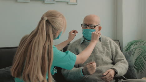 female caring nurse puts on face mask on elderly male