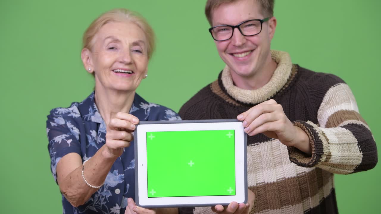 Happy grandmother and grandson showing digital tablet together