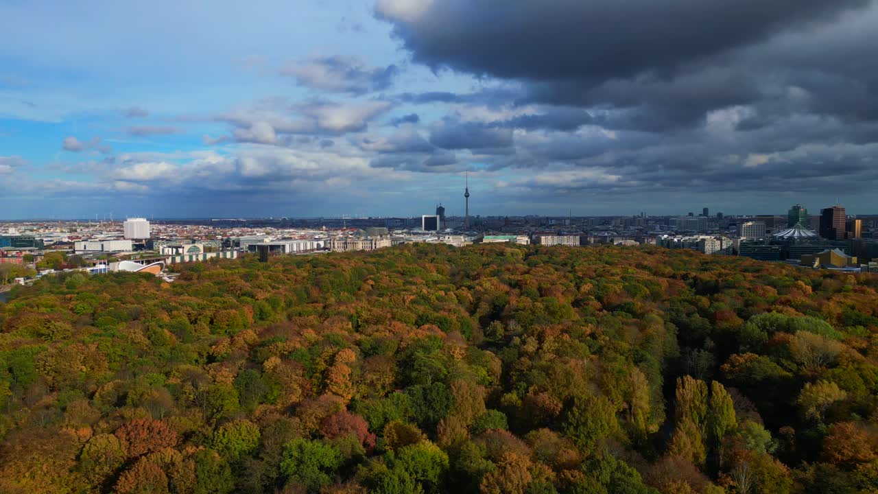 Berlin cityscape with fall colors of Tiergarten Park under cloudy sky. Majestic aerial view flight fly reverse overflight flyover drone