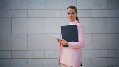 luxurious ceo walking street holding papers folder. businesswoman with cellphone